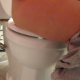 A girl farts, pees, and then takes a shit while sitting on a toilet - as seen from a camera positioned on the bathroom floor beside the toilet. Audible plops and grunting and can be heard. Over 4 minutes.